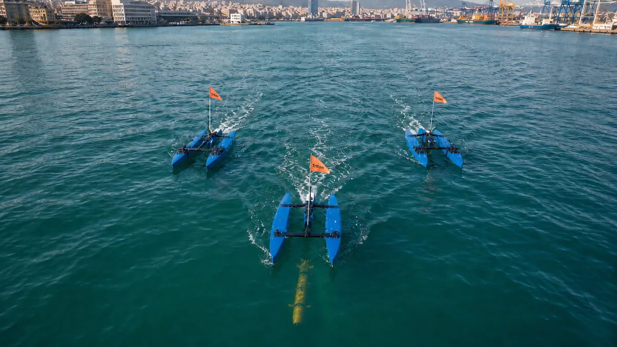Three BlueBoat USVs in coordinated triangular formation on Piraeus harbour, with a yellow UUV visible beneath the lead vessel